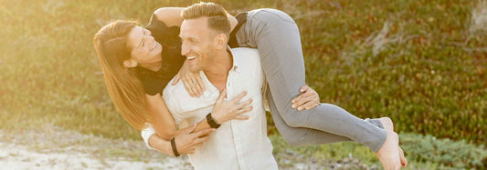 Man carrying a woman on his shoulders with both smiling