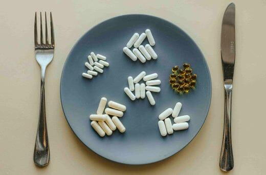 A plate containing pills with a fork and a dinner knife on the sides