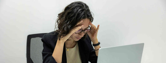 Woman sitting at a desk in front of a laptop showing frustration
