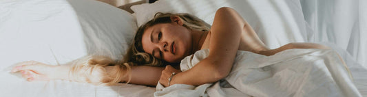 Woman sleeping on a bed with white sheets and pillows