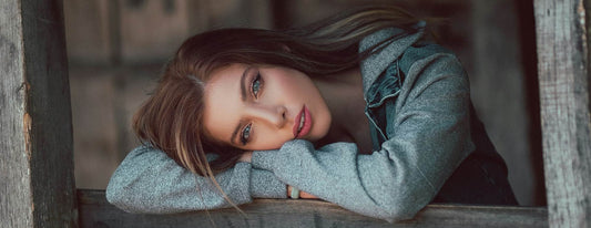 Woman laying her head on top of her cross arms, resting on the ledge of a fence