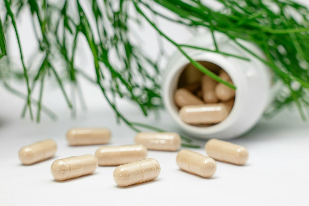 Supplement pills spread on a white surface, dropped from a bottle