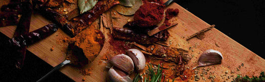 Several herbs and produce on top of a bamboo cutting board