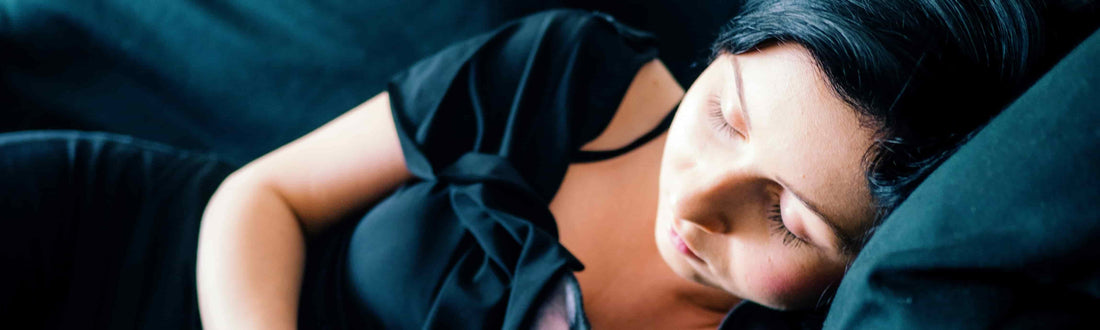 Young woman in a black dress sleeping on a couch