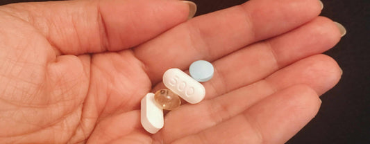 A hand holding 4 vitamin pills