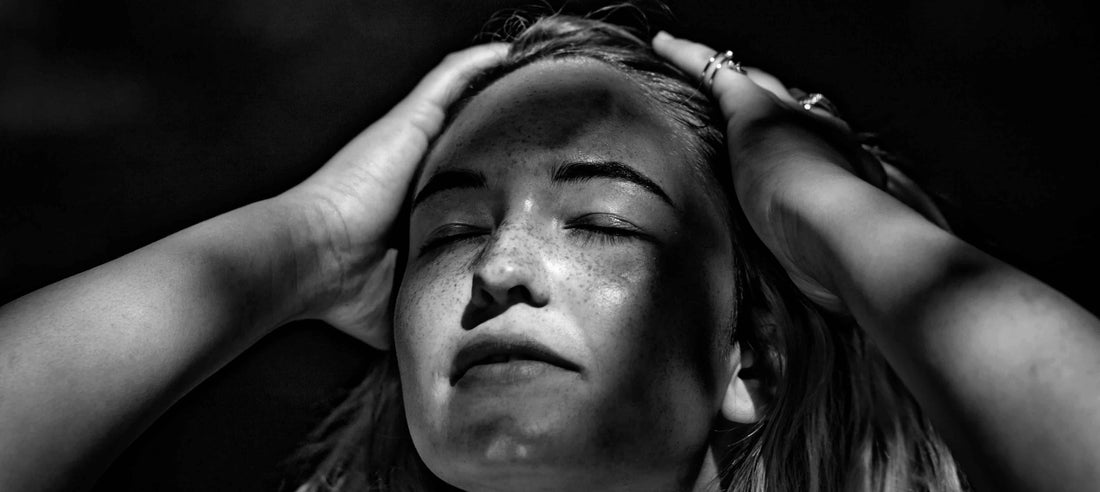 Woman with her hands over head and her eyes closed.