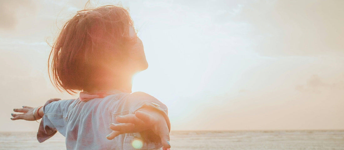 Woman with open arms viewing a sunset