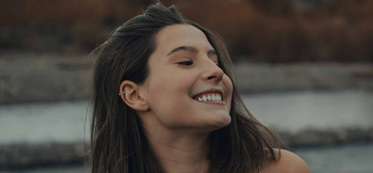 Brunette woman smiling near a river bank