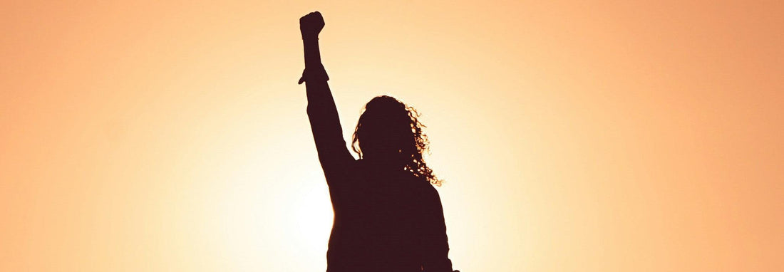 woman with one hand up in the sky showcasing her energy