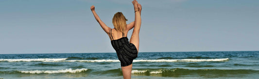 Woman in bathing suit doing yoga at the beach.