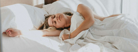 Woman sleeping in a bed with white linens