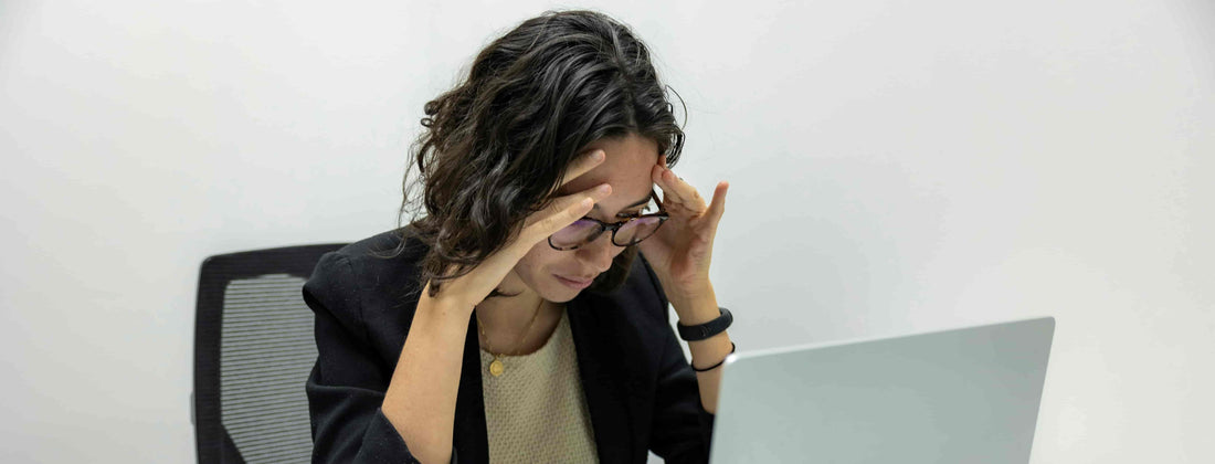 Woman sitting at a desk in front of a laptop showing frustration