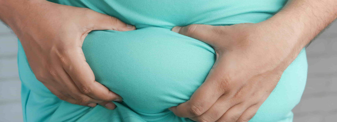 Person in a teal shirt holding the abdomen with both hands to show a roll